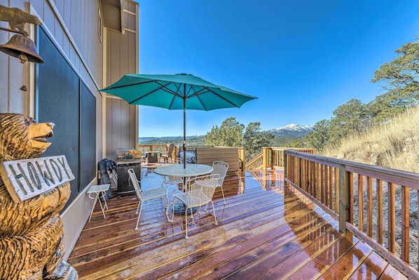 A wooden deck with a table and chairs, a green umbrella, and a sign that reads "HOWDY".