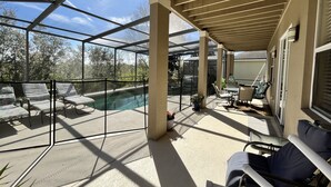 Ein überdachter Außenbereich mit Pool, Liegestühlen und einem Patio-Tisch.