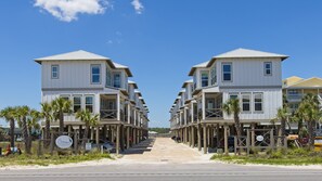 A row of beachfront buildings with balconies, a sign for 'The Cottage at Lagoon Pass', and a clear sky.