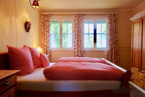 A bedroom with a bed, wooden wardrobe, and a window with curtains. - Kanne Cottage Flaire Suite with Stream and Meadow (Epfendorf/Trichtingen)