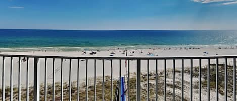 A beach with a clear view of the ocean and a railing in the foreground.