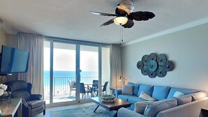 A living room with a sofa, armchair, and coffee table, a TV, and a balcony with a view of the ocean. - San Carlos 605 – Gulf-Front with Stunning Beach Views! (Gulf Shores)