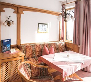 Ett mysigt rum med en träbänk, ett bord med en rosa duk och en vägglampa.