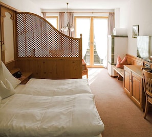 A bedroom with a wooden headboard, a bed with white linens, a desk with a chair, and a view of the outdoors through a large window. - Winklmoosalm Vacation Rental (Reit im Winkl)