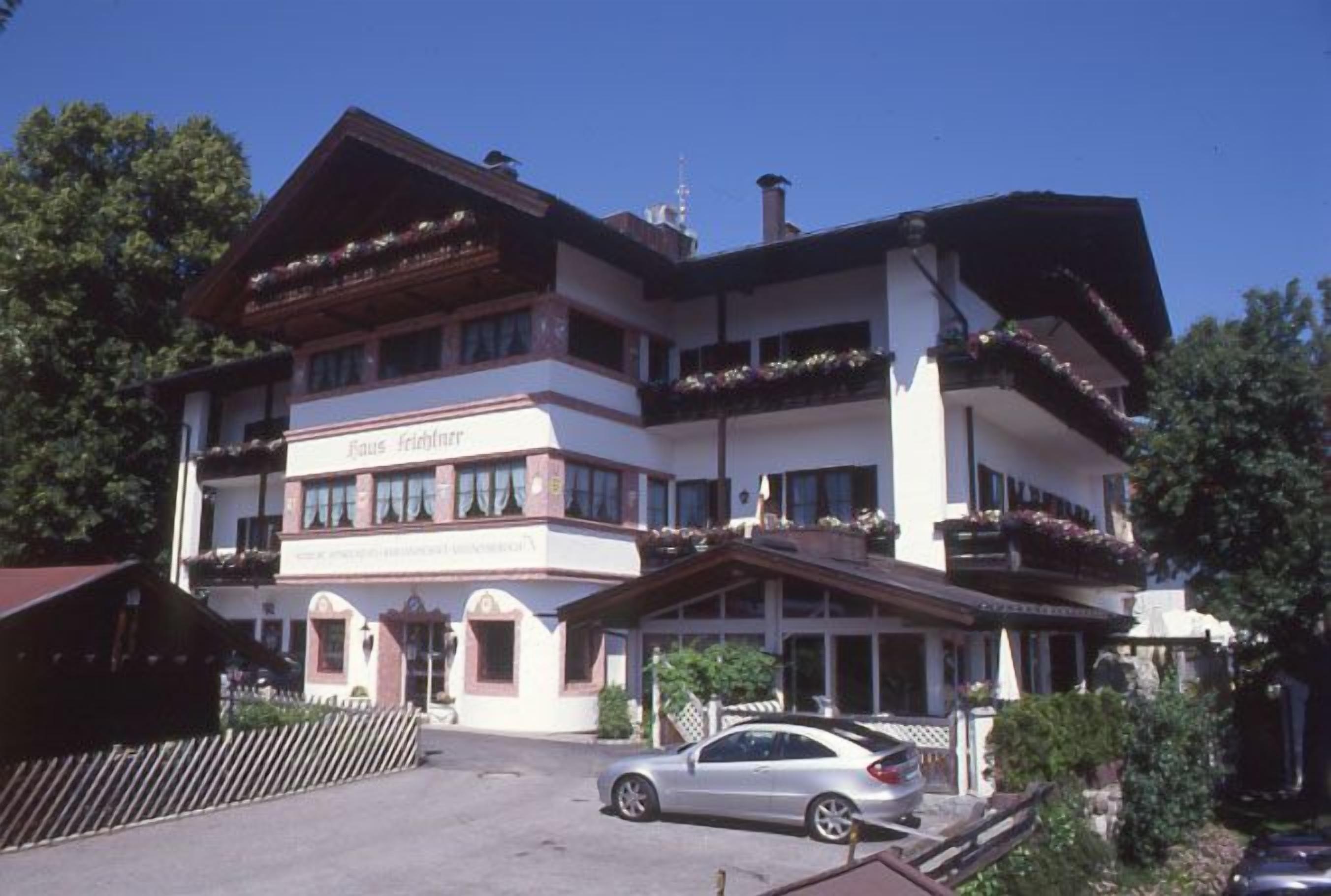 A multi-story hotel with balconies, a car parked in front, and a clear sky.