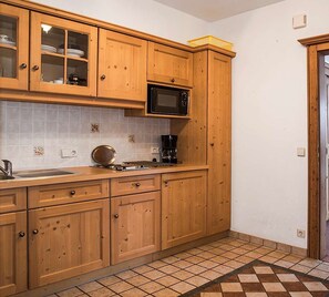 A kitchen with wooden cabinets, a microwave, a coffee maker, and a tiled backsplash. - Kaiser Apartment in a Central Location (Reit im Winkl)