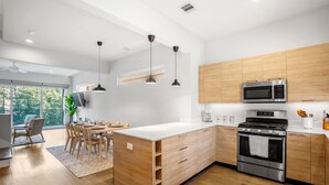 A modern kitchen with wooden cabinets, a stainless steel stove, and a large island with a sink. - Ethereal Rooftop Retreat - 1 km from FIFA Fest (Houston)