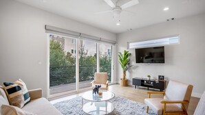 A modern living room with a sofa, two armchairs, a coffee table, and a TV mounted on the wall. - Ethereal Rooftop Retreat - 1 km from FIFA Fest (Houston)