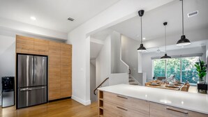 A modern kitchen with a stainless steel refrigerator, wooden cabinets, and a white countertop. - Ethereal Rooftop Retreat - 1 km from FIFA Fest (Houston)