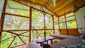 Una cabaña de madera con ventanas grandes, un ventilador de techo y una mesa con un florero.