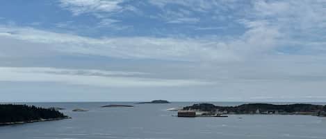 Un paisaje costero con una gran masa de agua, varias islas pequeñas y una costa distante con edificios.