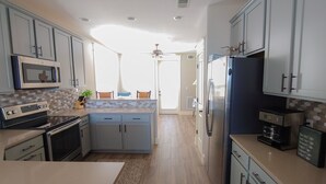 A modern kitchen with grey cabinets, a central island, a microwave, a stove, and a refrigerator.