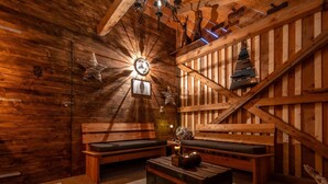 Interior acolhedor de uma cabana de madeira, com um banco, uma mesa pequena e uma escada.