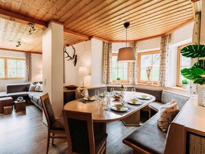 Un comedor acogedor con una mesa de madera dispuesta para cuatro personas, rodeado de asientos con cojines.