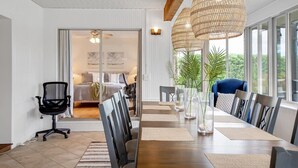 A modern dining area with a long wooden table, black office chairs, and a large woven pendant light. - Private Corner Oasis with Heated Saltwater Pool (Palm Coast)