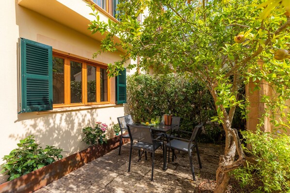 Un patio con tavolo e sedie, una finestra con persiane e un albero.