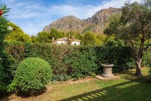 Une maison entourée d’une végétation luxuriante, avec une chaîne de montagnes en toile de fond.