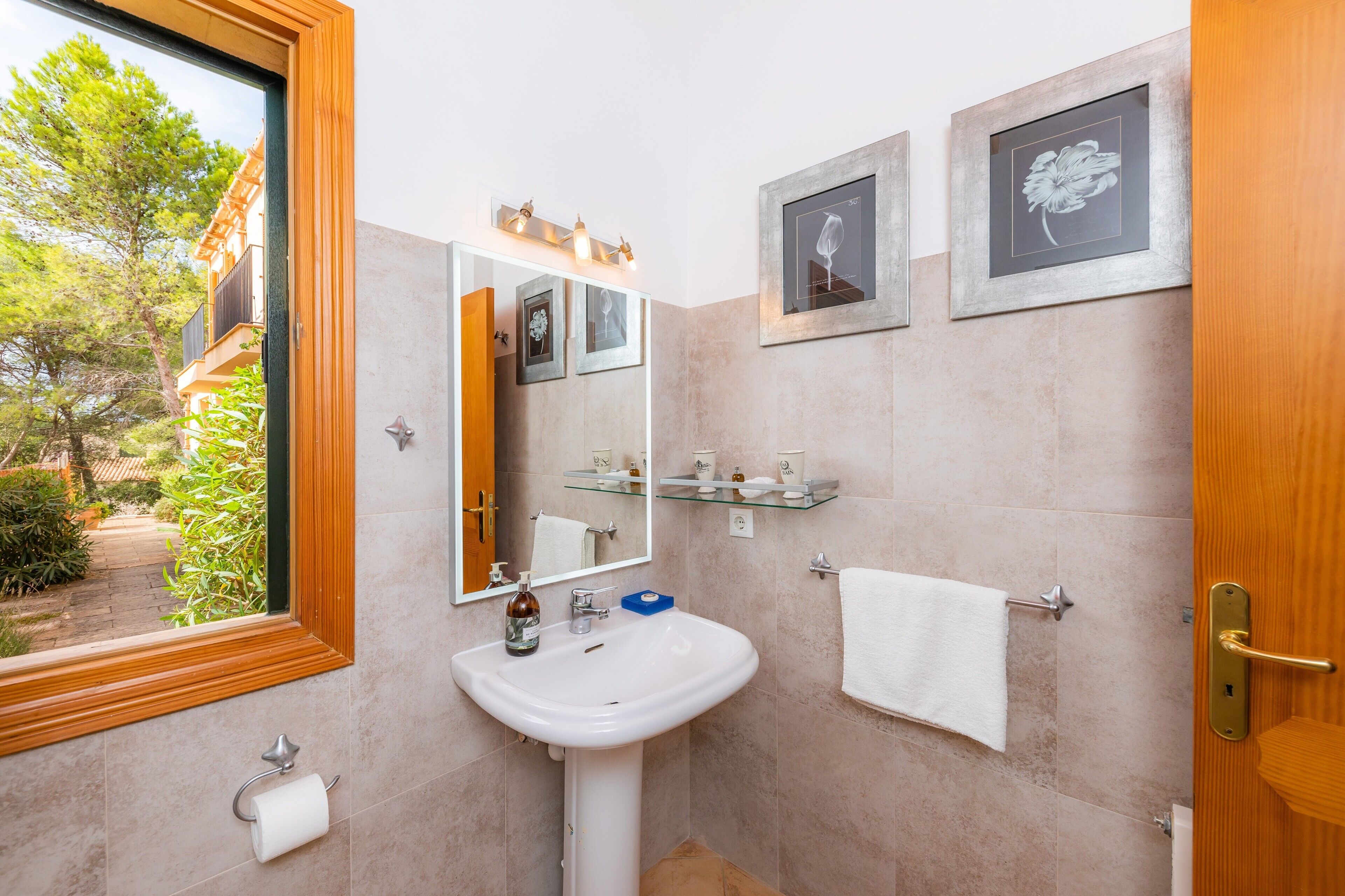Une salle de bain équipée d’un lavabo, d’un miroir, d’un porte-serviettes et d’une œuvre d’art encadrée au mur.