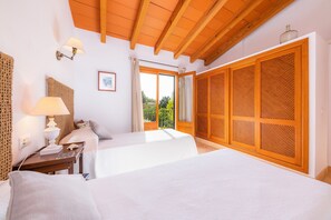 Une chambre d’hôtel avec deux lits, un plafond en bois, une grande fenêtre et une armoire au design ajouré.