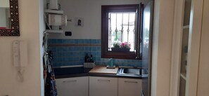 Eine kleine Küche mit Fenster, Spüle, Arbeitsplatte und Schränken.