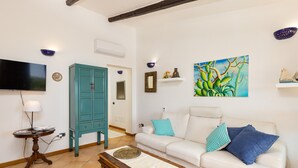 Uma sala de estar com um sofá branco, um armário verde-água e um quadro na parede.