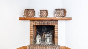 A fireplace with three woven baskets on the mantel, two white candle holders, and a brick surround.
