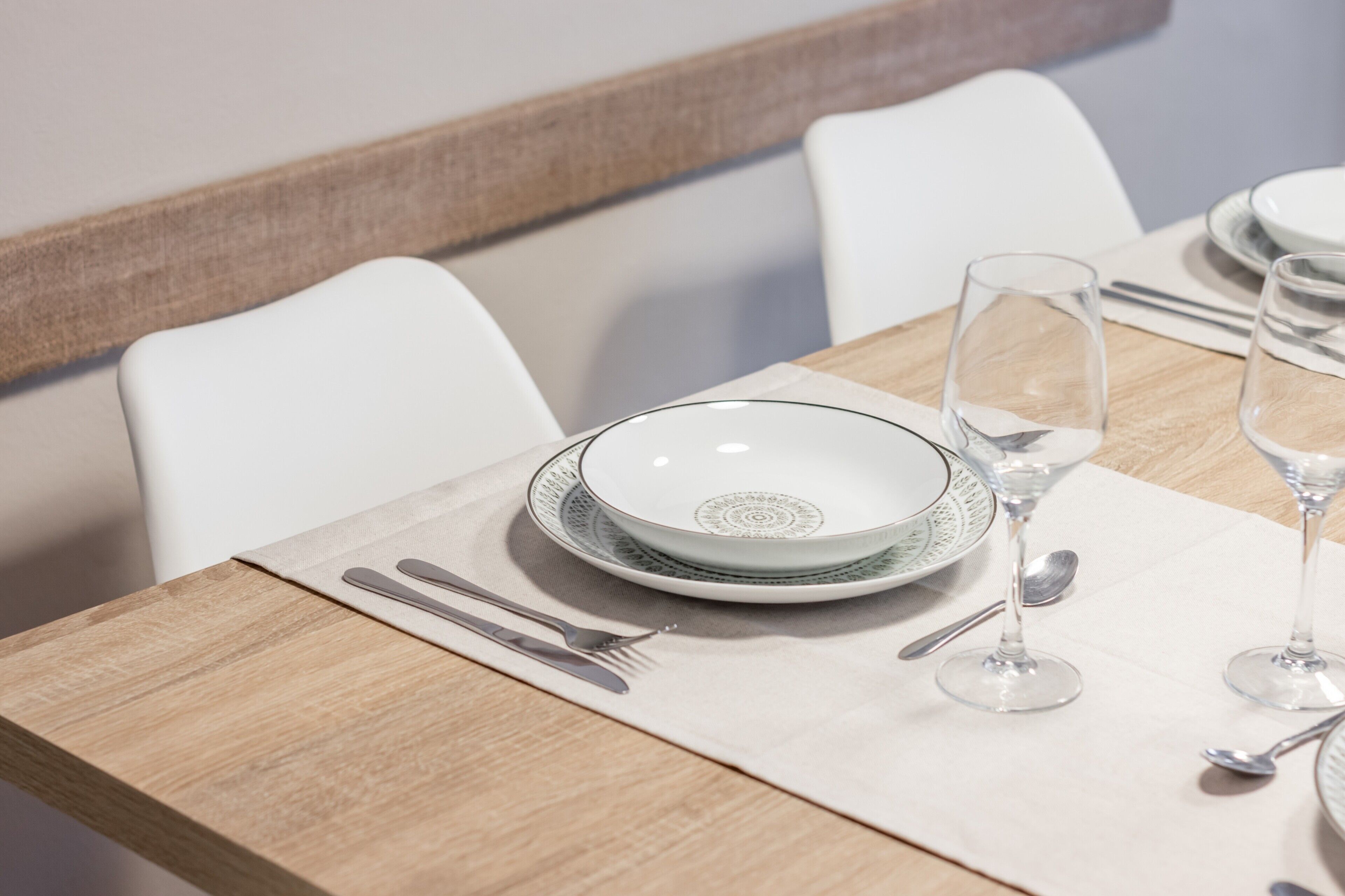 Une table à manger dressée avec des assiettes, des verres et des couverts.