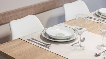 Une table à manger dressée avec des assiettes, des verres et des couverts.