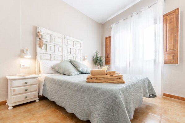 A bedroom with a bed, nightstand, lamp, and curtains. - Apartment Can Tosca with Patio, A/C & WLAN; Garage Available (Jávea)