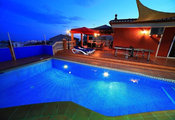 Une piscine dotée d’une terrasse carrelée, de chaises longues et d’un espace salon abrité.