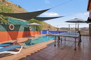 Zona de piscina con mesa y sillas, un flotador salvavidas y vistas del paisaje.