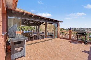 Un patio exterior con una parrilla, una mesa de comedor y sillas.