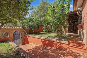 Un patio con un camino de ladrillo, un muro de piedra y una reja.