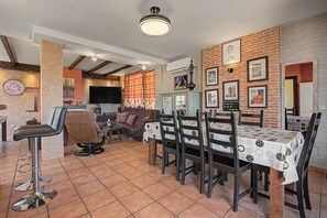 Een eetruimte met een tafel voor vier personen, omringd door houten stoelen, in een kamer met bakstenen muren en een betegelde vloer.
