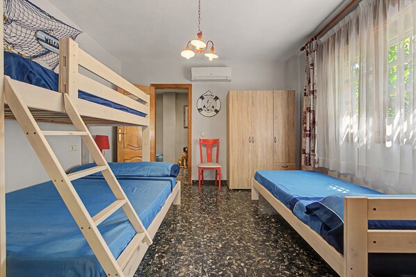 Una habitación con literas, un escritorio, una silla, un armario y un reloj de pared.