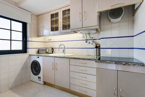 Cocina compacta con lavadora, lavamanos y armarios.