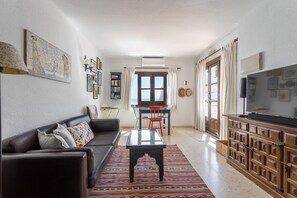A living room with a sofa, a coffee table, a TV, a bookshelf, and a dining area with a table and chairs. - Apartment "Capistrano Playa" - Wi-fi, air-conditioning, pool, sea view. (Nerja)