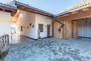 Un bâtiment doté d’un patio carrelé, de portes en bois et d’un mur en pierre.