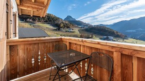A wooden deck with a table and chairs, overlooking a mountainous landscape. - Apartment "Guntschöllerhof Völseggspitze" with Mountain View, Wi-Fi, Balcony & Garden (Völs)