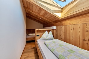 A small, wooden room with a bunk bed and a skylight.
