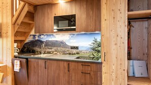 Une cuisine dotée de meubles en bois, d’un four à micro-ondes encastré et offrant une vue imprenable sur un paysage montagneux.