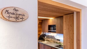 Une enseigne en bois avec du texte, une cuisine avec des meubles en bois et une vue sur un paysage par la fenêtre.
