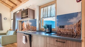 A modern kitchen with wooden cabinets, a built-in microwave, and a window with a view of mountains.