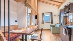 A wooden interior with a dining table, bench, and kitchen area.