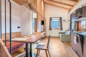 Ein Holzinterieur mit Esstisch, Bank und Küchenzeile.