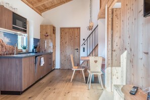 Eine Küche mit Holzausstattung, einer Mikrowelle und einem Essbereich mit Stuhl und Tisch.