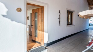 Ein Flur mit einer Holztür, einem kleinen Fenster und einer Wandleuchte.