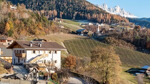 Eine Berglandschaft mit Weinbergen, einem weißen Gebäude mit Balkon und einer Kirche.