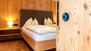 Ein Zimmer mit Holzboden, einem Bett, einem Nachttisch mit Lampe und einer Tür mit Schloss.