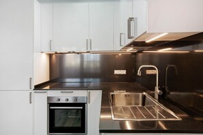 Una cocina moderna con electrodomésticos de acero inoxidable, horno integrado y un lavamanos.